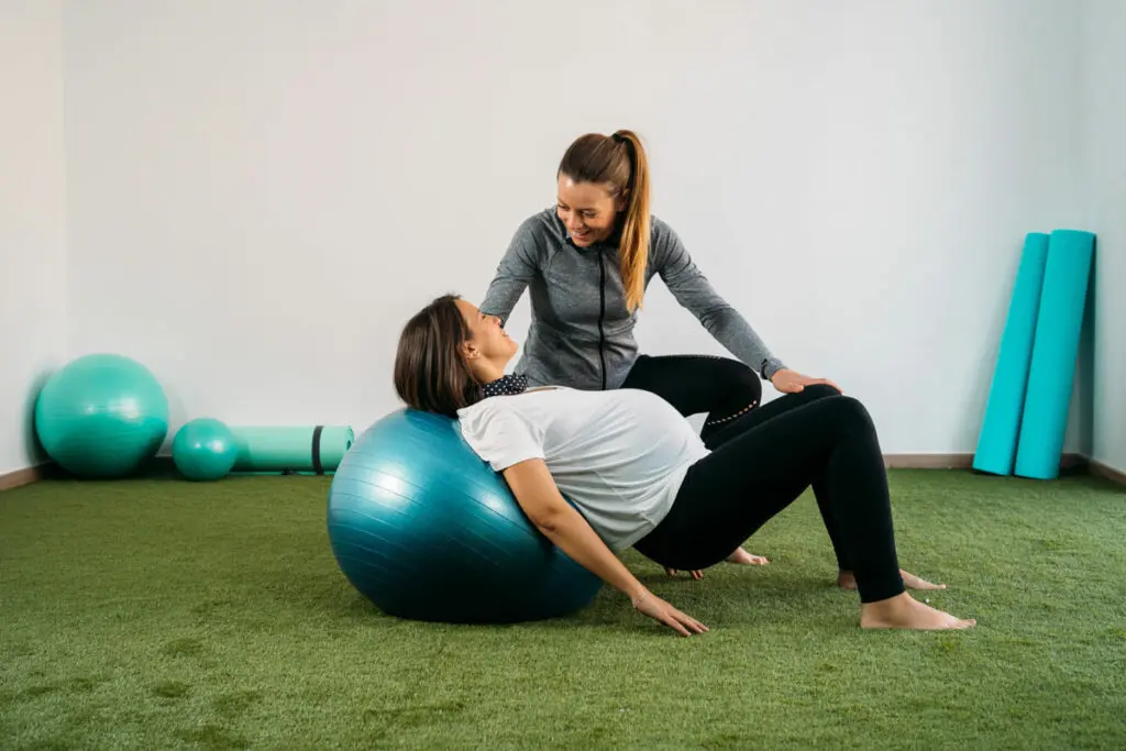 Pregnant woman doing pilates with instructor